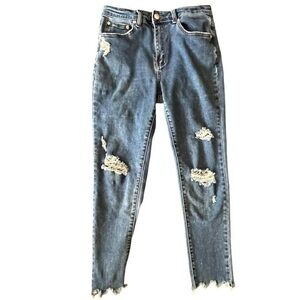 High rise skinny blue jeans with distressed knees, zip fly, and button closure.